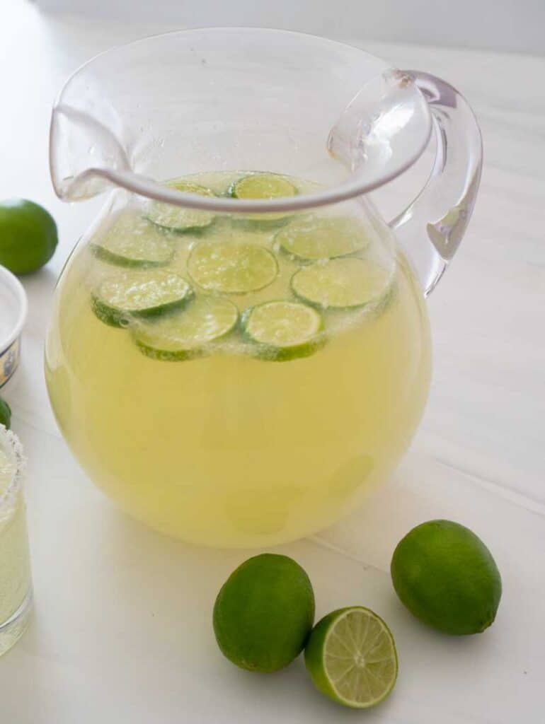 nonalcoholic margarita punch in clear pitcher with limes