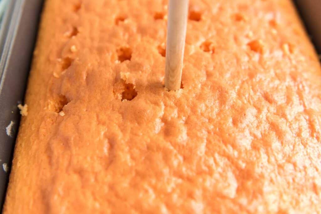 skewer poking holes in orange cake