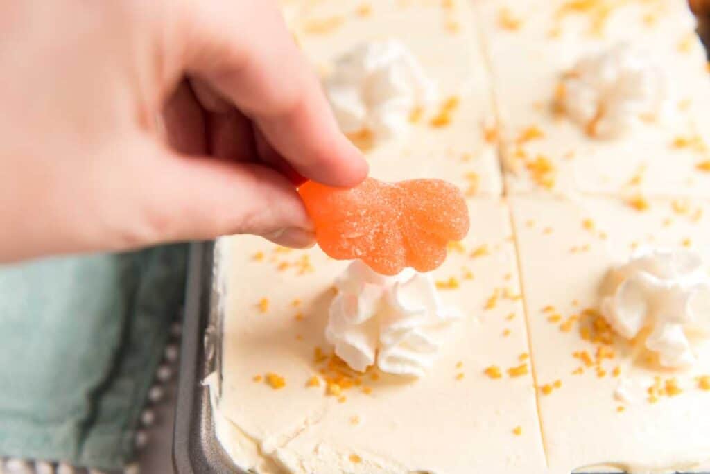 placing orange candy on a orange creamsicle poke cake