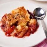 piece of cherry pineapple dump cake on a white plate with a spoon