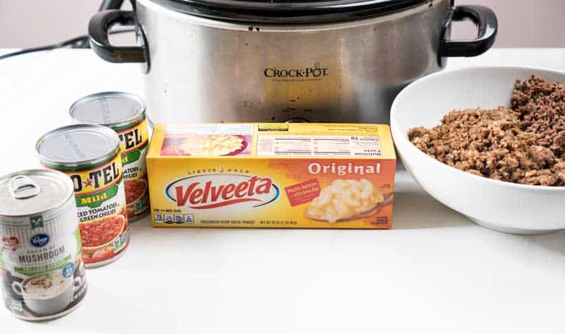 crock pot with velveeta, rotel, cream of mushroom soup, ground beef and ground sausage for slow cooker queso cheese dip