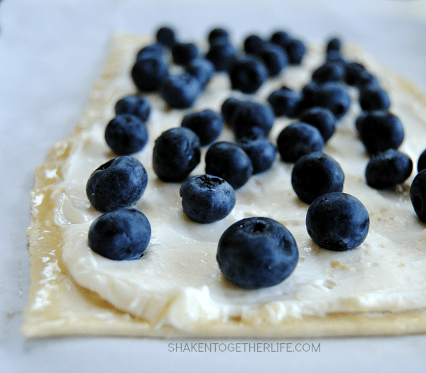 This Blueberry Lemon Cheesecake Tart is SO delicious! Golden flaky puff pastry is topped with a lemon cheesecake filling and fresh blueberries!