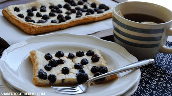 This Blueberry Lemon Cheesecake Tart is SO delicious! Golden flaky puff pastry is topped with a lemon cheesecake filling and fresh blueberries!