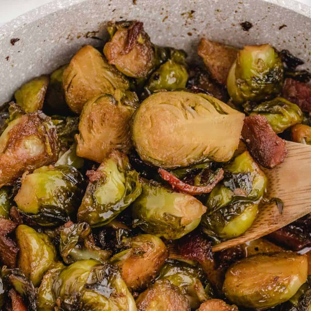 close up of brown sugar bacon brussels sprouts and wooden spoon