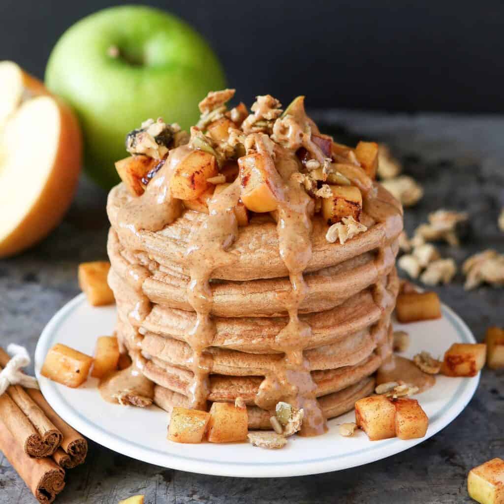 stack of pancakes with apples and syrup