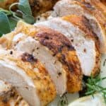 sliced roasted turkey breast on plate with herbs