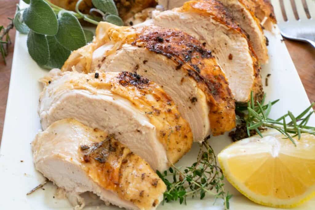 sliced roasted turkey breast on plate with herbs