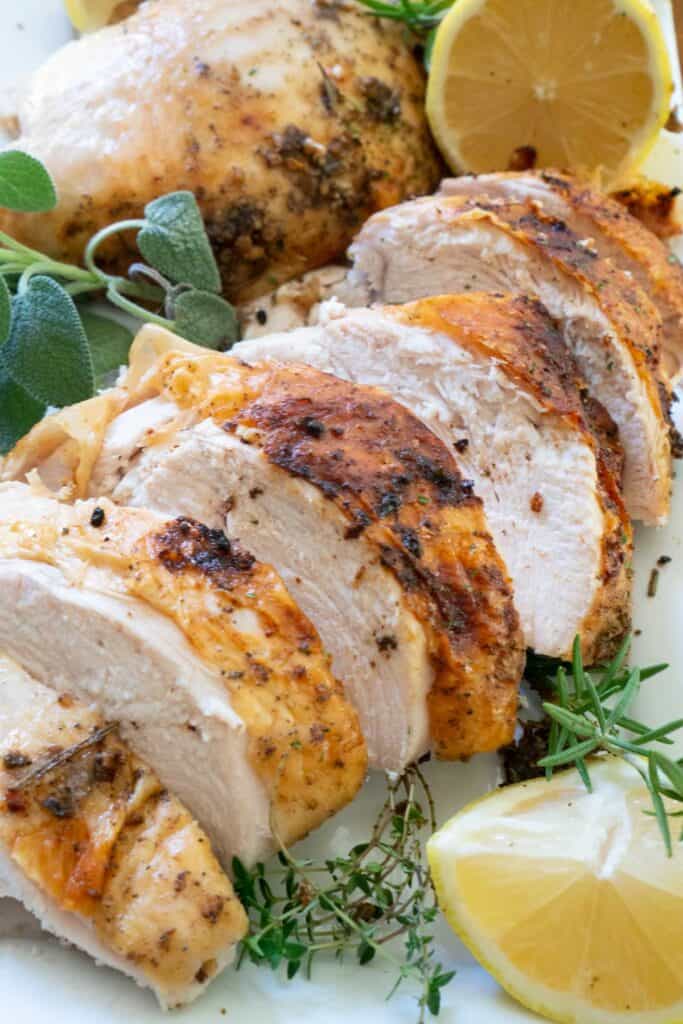 sliced roasted turkey breast on plate with herbs