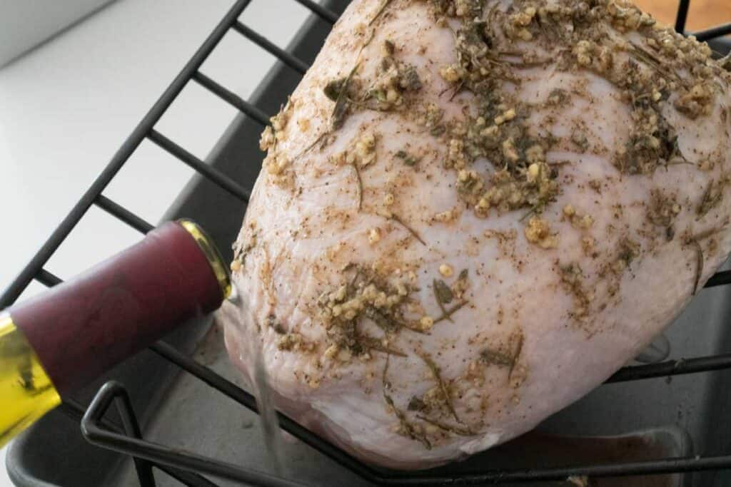 pouring wine into roasting pan with raw turkey breast