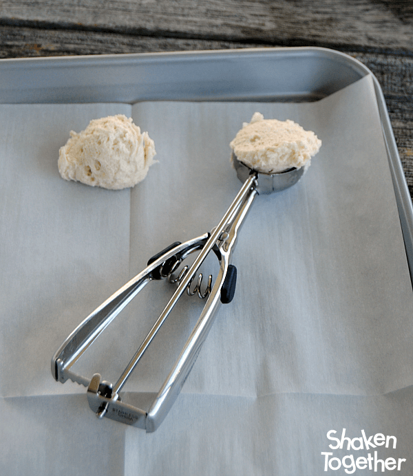 A cookie scoop with dough for Lemon Coconut Sugar Cookies