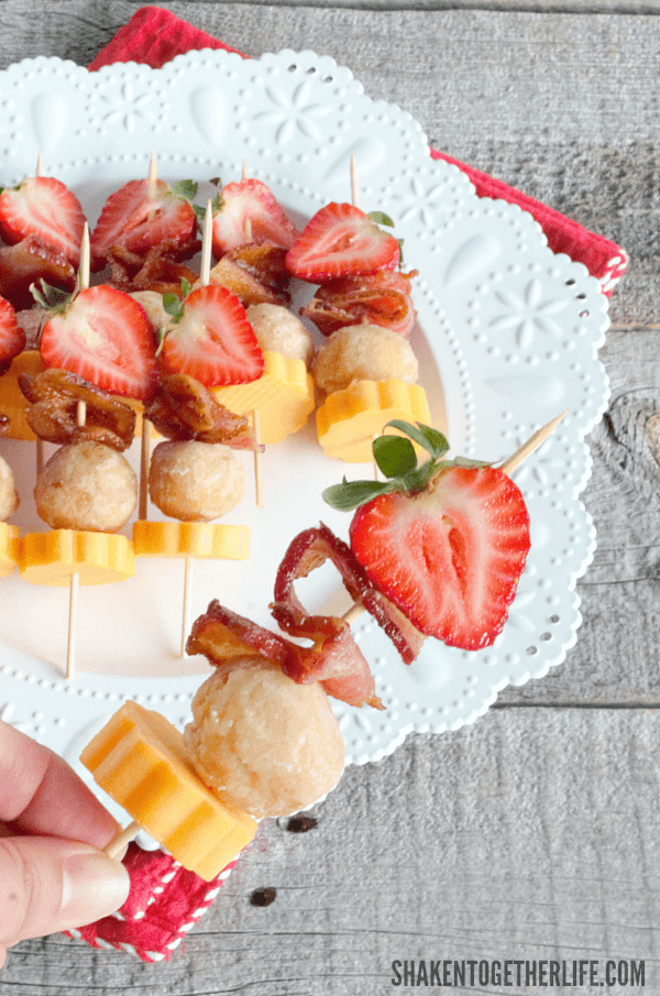 Berry Brunch Kabobs on white plate with hand holding one close up