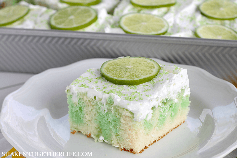 Lime Poke Cake is a simple but stunning dessert! White cake, drenched in lime Jell-O and topped with fluffy whipped topping and lime slices, this easy lime cake is a stunner!