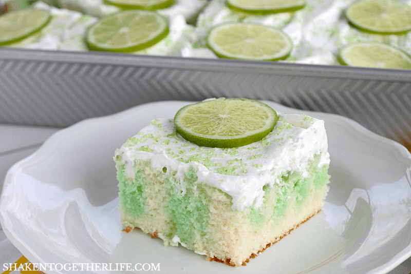 piece of Lime Poke Cake topped with slice of lime on white plate