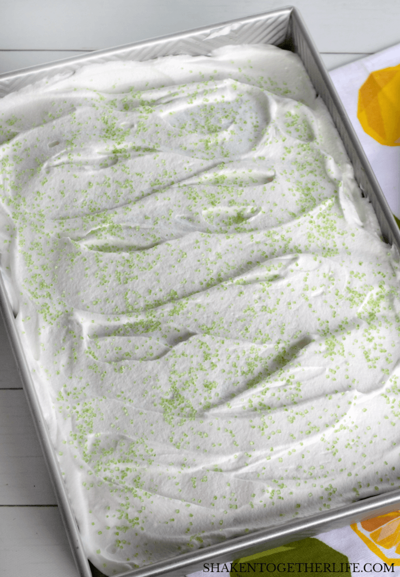 lime poke cake from above topped with whipped cream and green sprinkles