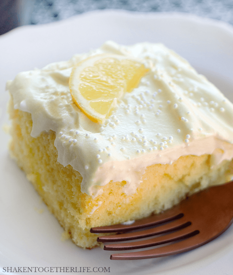 lemon poke cake topped with lemon slice on white plate