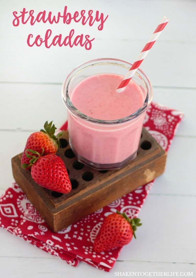 Creamy Frozen Strawberry Colada on wood block with patterned red and white napkin and whole strawberries