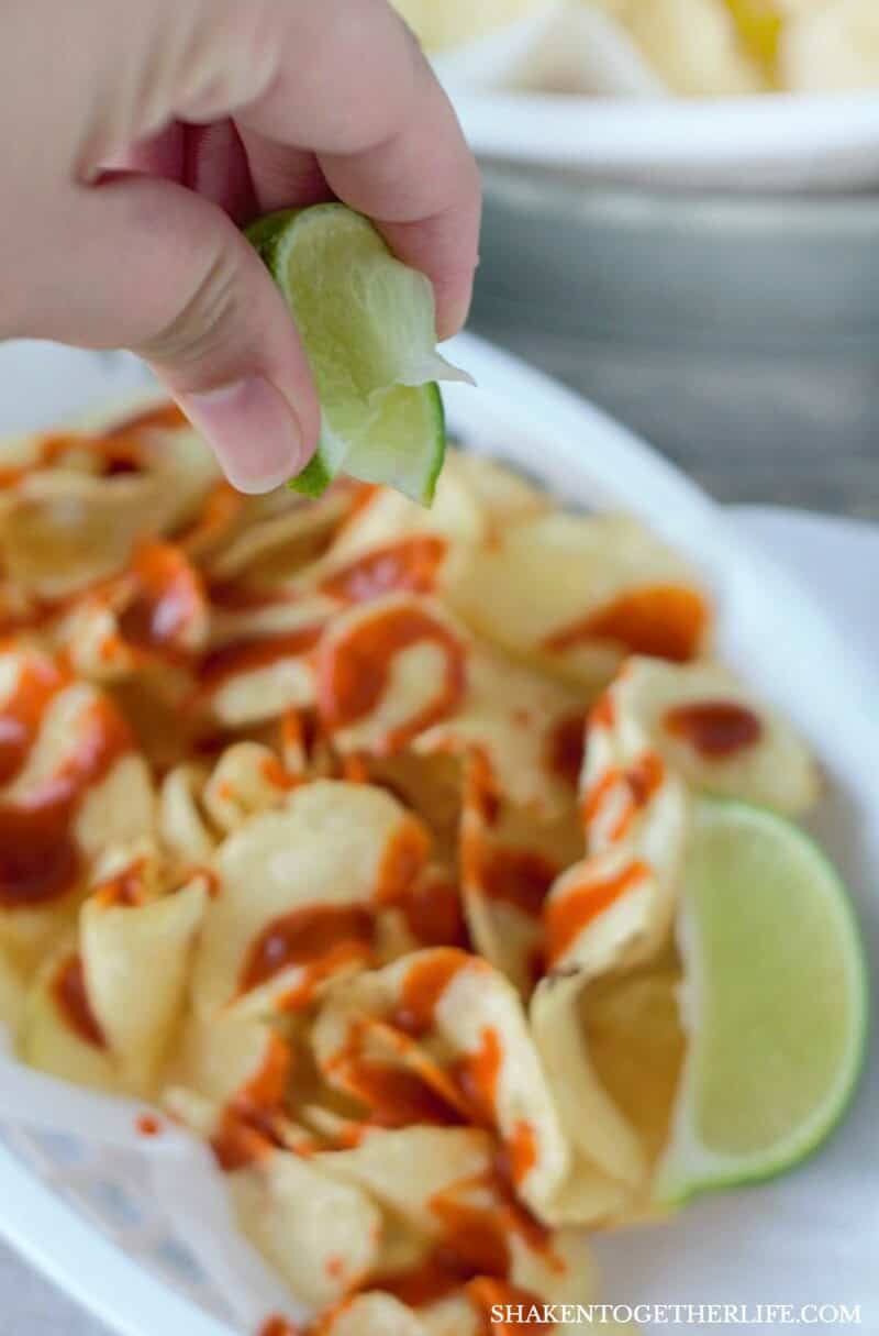 Squeezing lime wedge over Mexican Street Chips 