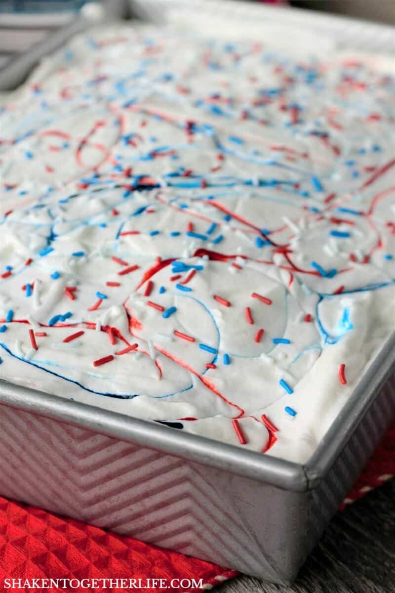 Red, White & Blue Poke Cake is topped with food coloring fireworks and sprinkles ... but wait until you cut a piece of this easy patriotic dessert!