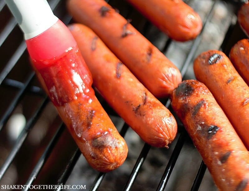 brushing Smoked Sausage with bBQ sauce while grilling