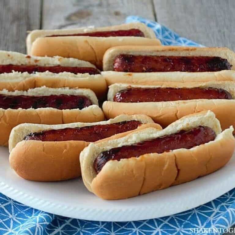 glazed smoked sausages in buns on white plate