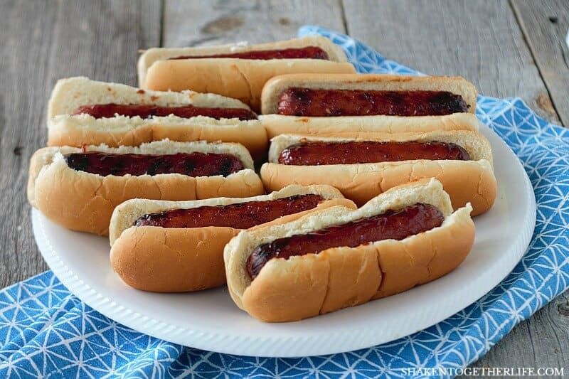 Grilled BBQ Glazed Smoked Sausages in buns on white plate