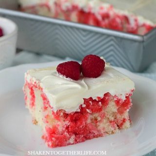 Soft white cake is drenched in raspberry Jell-O then topped with fluffy whipped cream and fresh raspberries - this super simple Raspberry Poke Cake is definitely a dreamy dessert!