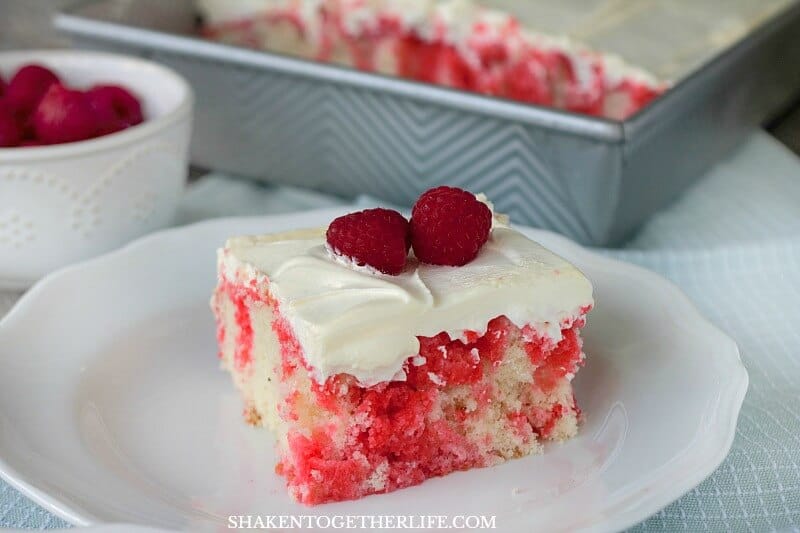 Soft white cake is drenched in raspberry Jell-O then topped with fluffy whipped cream and fresh raspberries - this super simple Raspberry Poke Cake is definitely a dreamy dessert!