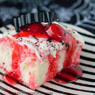 Cherry Vanilla Vampire Poke Cake on black and white striped plate