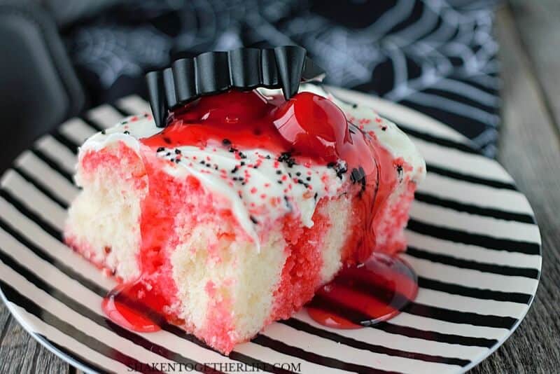 Cherry Vanilla Vampire Poke Cake on black and white striped plate