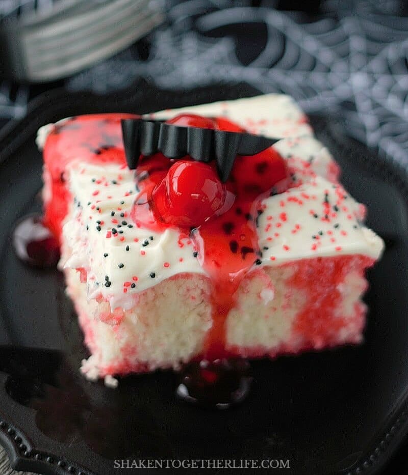 Each slice of Cherry Vanilla Vampire Poke Cake gets a pool of cherry pie filling and vampire fangs!