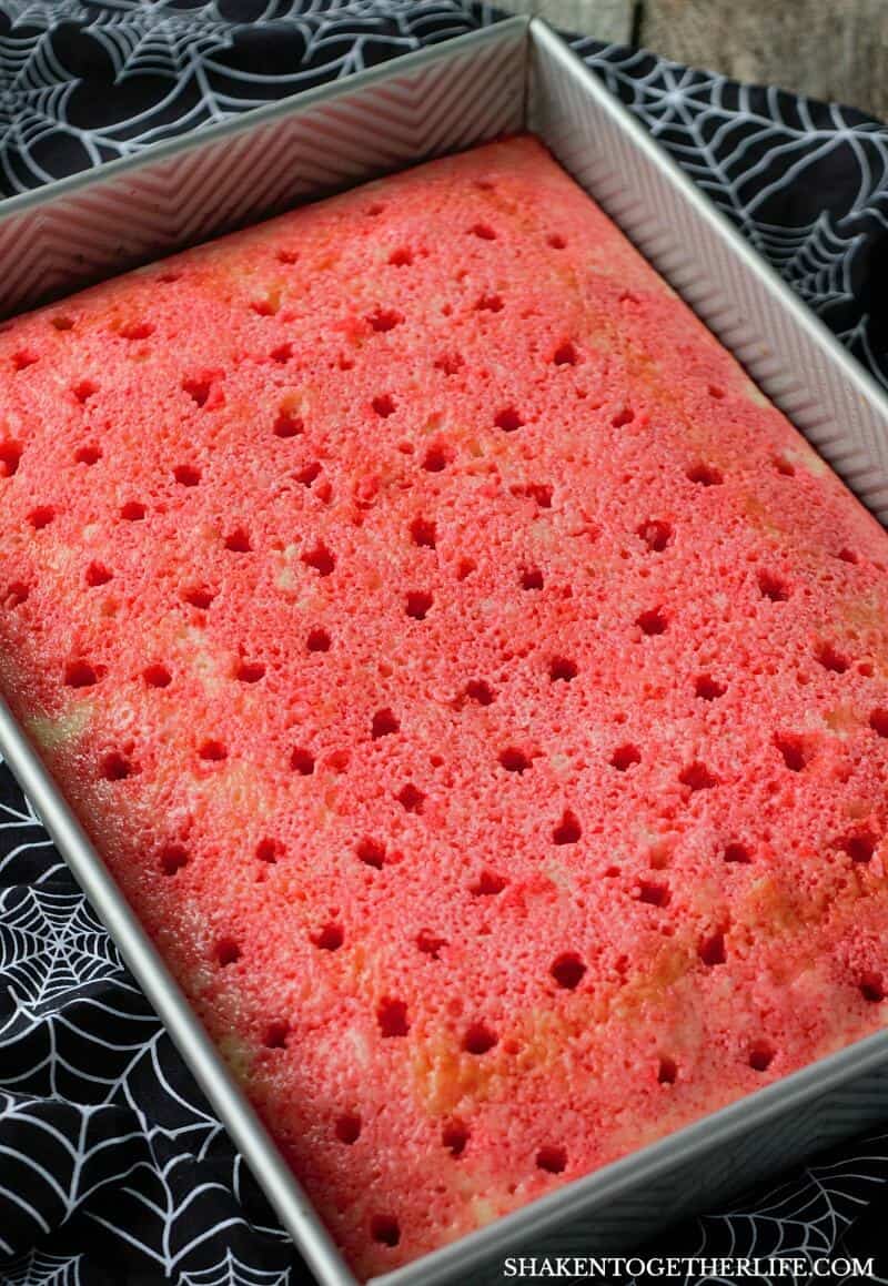 Cherry Vanilla Vampire Poke Cake starts with a vanilla cake soaked with cherry Jell-o