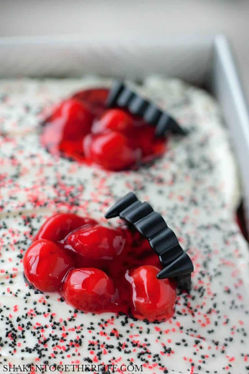 Next, the Cherry Vanilla Vampire Poke Cake gets glossy globs of cherry pie filling and vampire fangs!