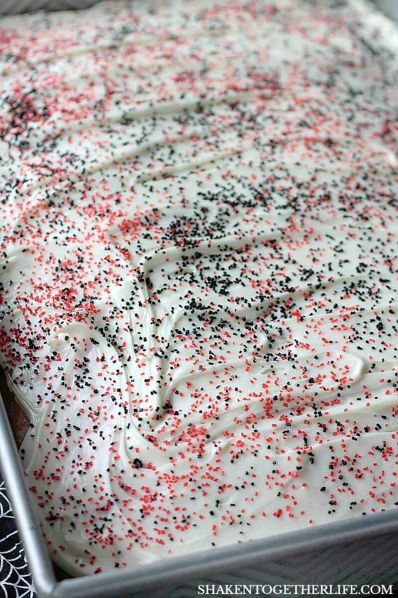 Cherry Vanilla Vampire Poke Cake is topped with a simple vanilla frosting and lots of black and red sugar sprinkled on!