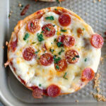 close up of thin bagel pizza on baking sheet