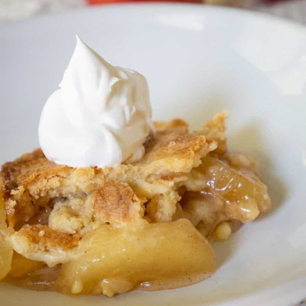 apple dump cake on white plate with whipped cream