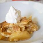 apple dump cake on white plate with whipped cream