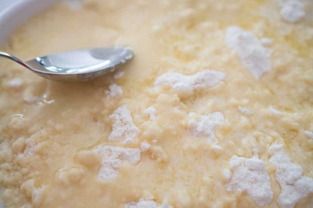 spoon spreading melted butter over cake mix