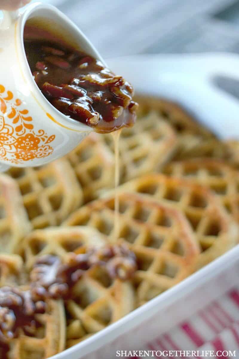 Overnight Waffle Breakfast Casserole pouring Brown Sugar Pecan Sauce in white casserole dish