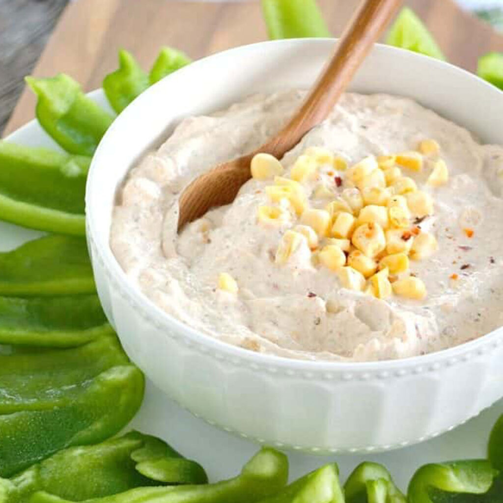 chipotle ranch dip in white bowl with sliced bell peppers