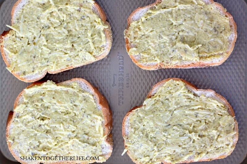 slices of bread with butter and pesto on them before baking