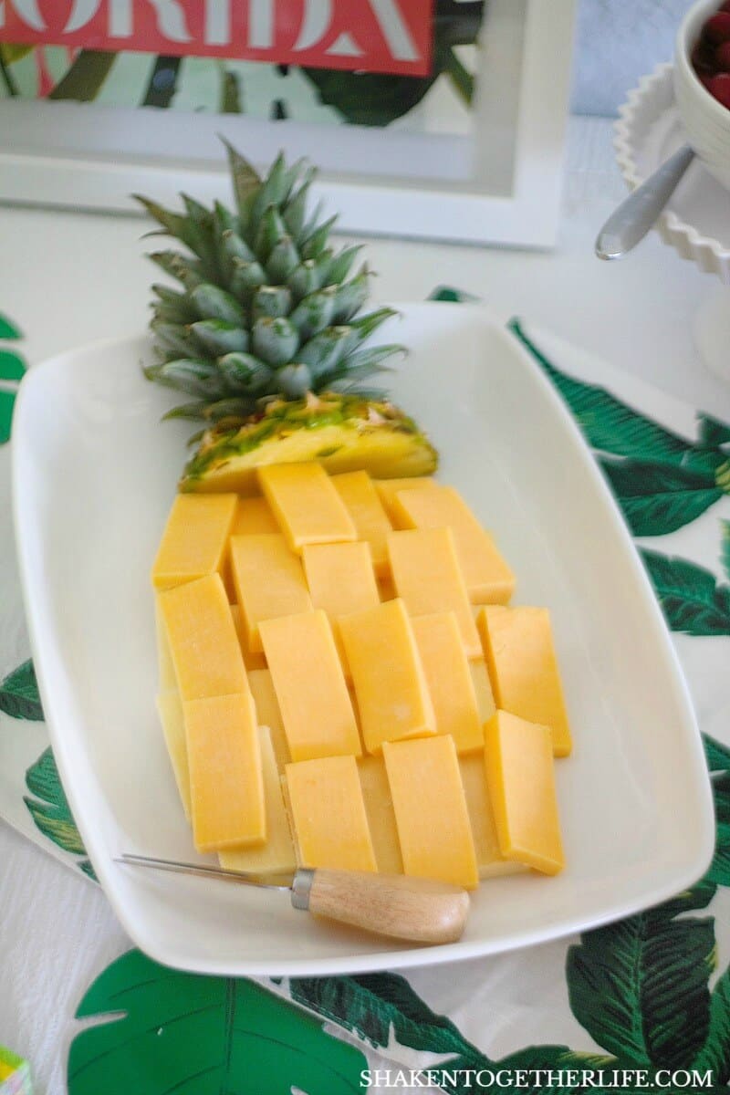 A pineapple shaped cheese tray is festive and easy to make for a Tropical Summer Craft Party! Ask the produce manager in your grocery store for the top of a pineapple to add to the cheese tray!