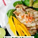 grilled grouper on plate with spinach and yellow bell pepper slices and text reading grilled grouper with lime butter