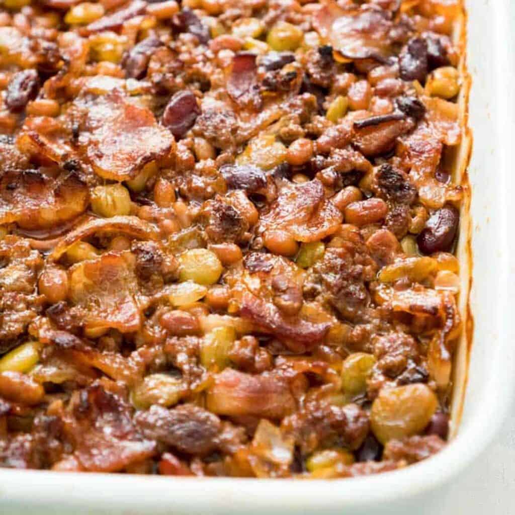 close up of calico baked beans in white casserole dish