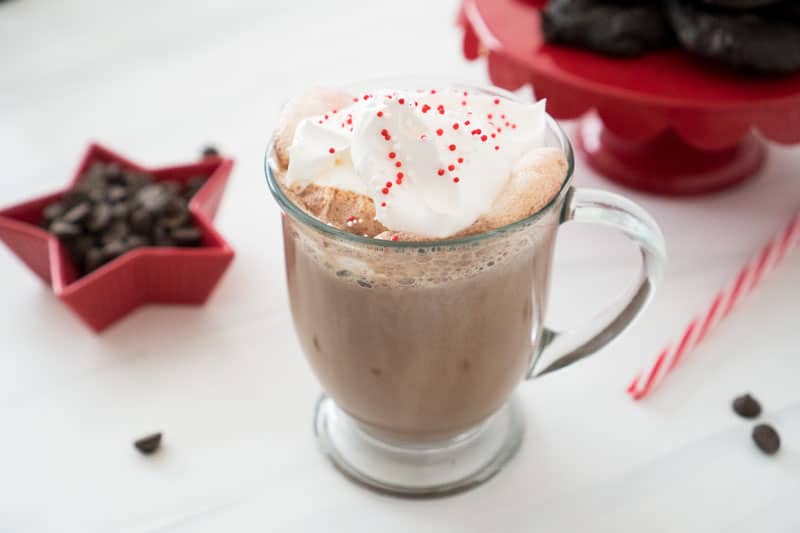 peppermint hot chocolate in glass mug with cookies in background