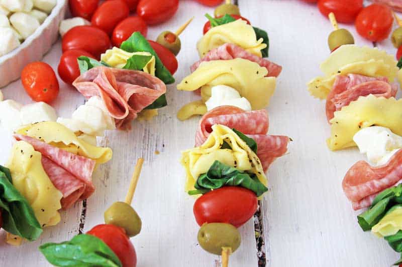 anitpasto skewers on white wood table