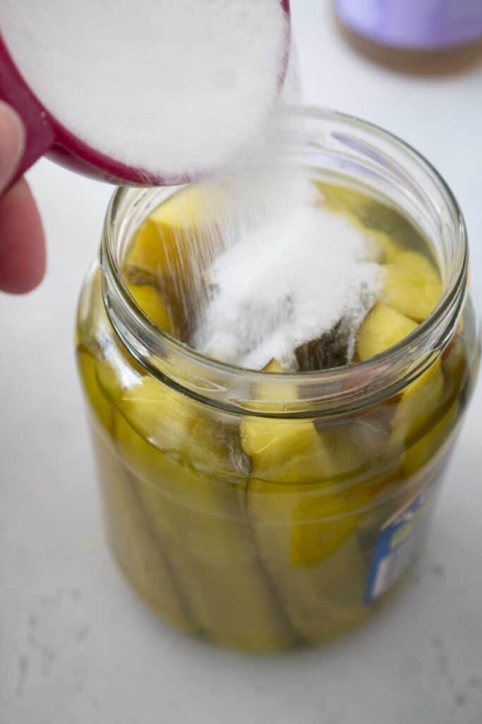 pouring sugar into pickle jar to make kool aid pickles