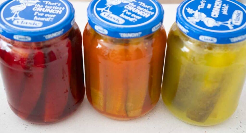 three jars of kool aid pickles, cherry, orange, and lemonade flavored