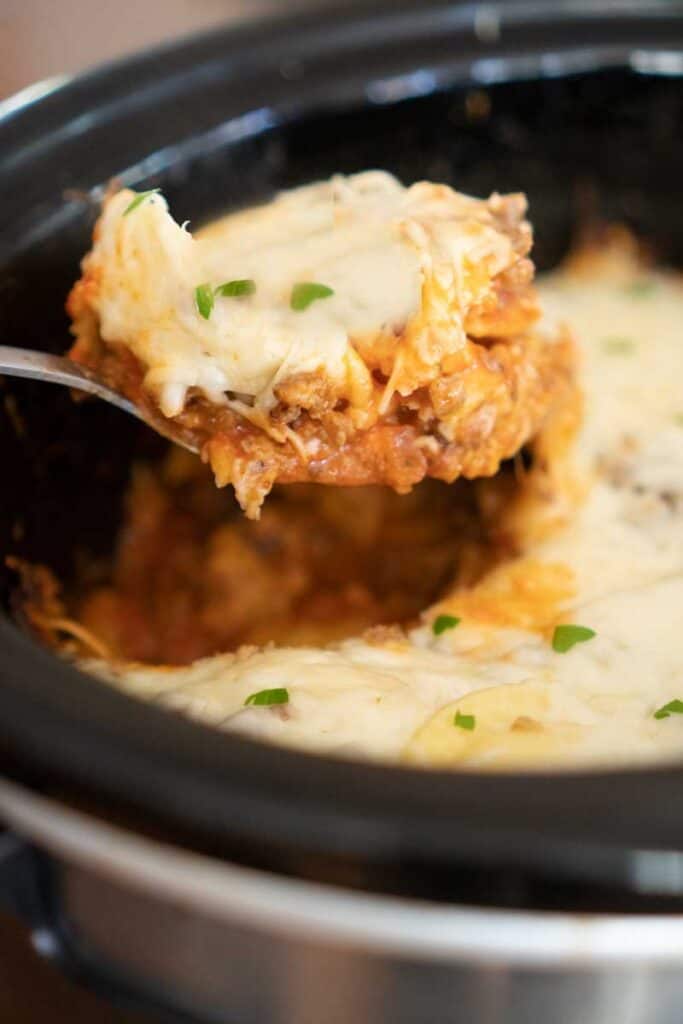 crock pot lasagna scooped out of slow cooker with large spoon