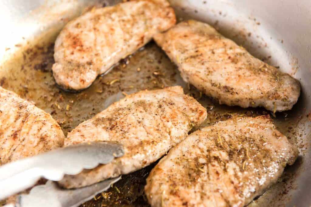 searing pork chops in a skillet