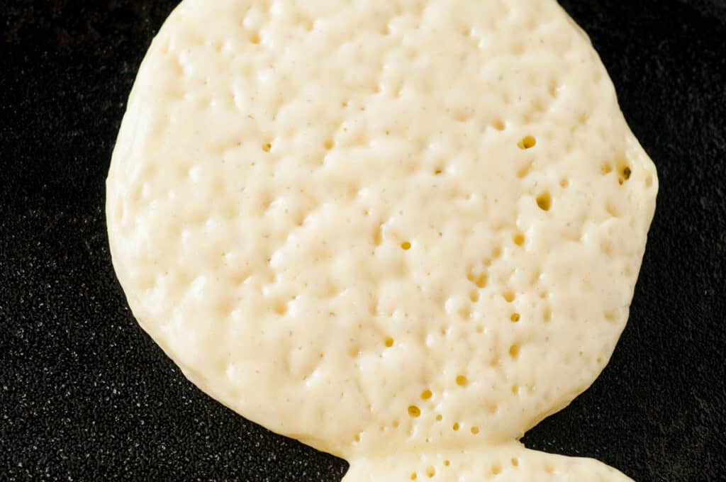pancake on griddle ready to be flipped with bubbling